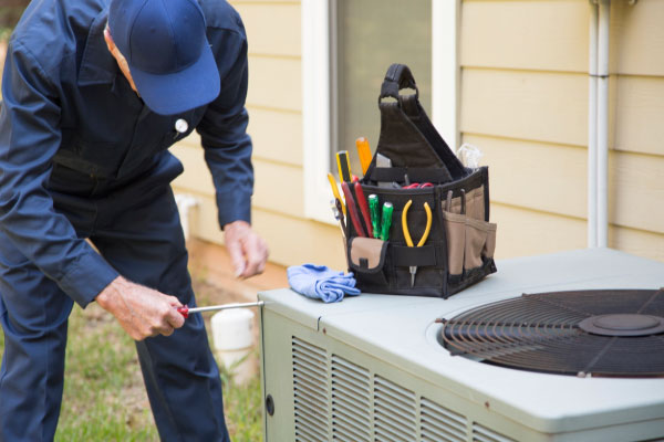 HVAC technician servicing air conditioning unit